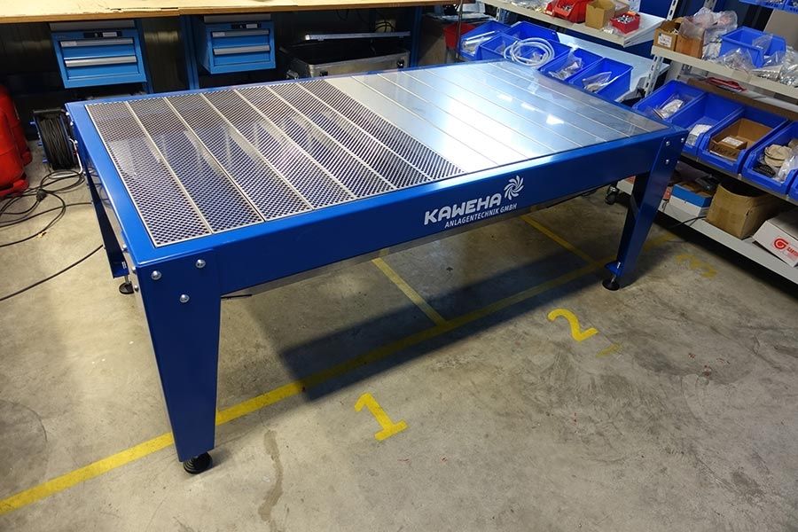 Extraction table with a grating surface and a blue frame in a workshop