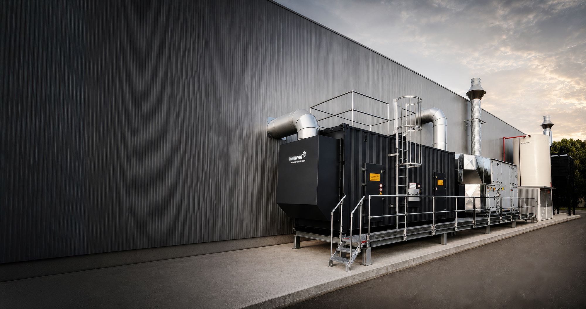 Industrieanlage in einem Container vor einer grauen Wellblechfassade unter bewölktem Himmel