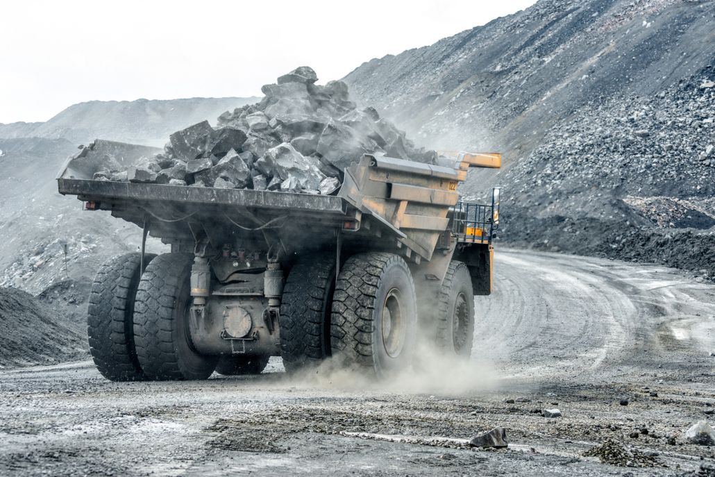 Beladener Muldenkipper mit Gestein in einem Steinbruch, aufgewirbelter Staub an den Rädern