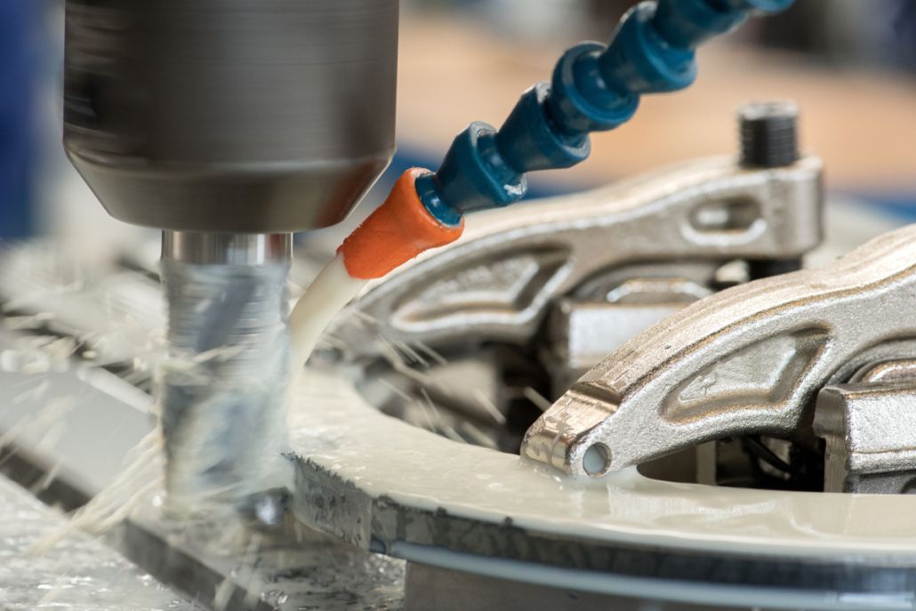 Nahaufnahme einer Metallbearbeitung, Bohrer mit Kühlschmierstoff-Zufuhr über eine Düse, Späne und Emulsion am Werkstück