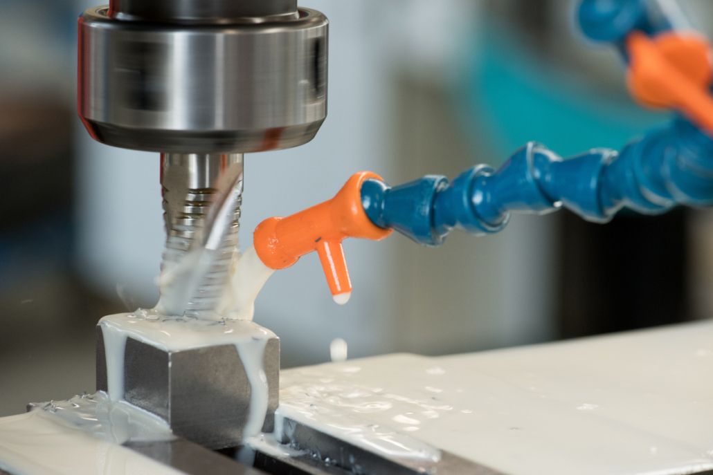 Nahaufnahme einer Fräsbearbeitung, Fräser über einem Werkstück mit Kühlschmierstoff-Zufuhr über eine orange-blaue Düse