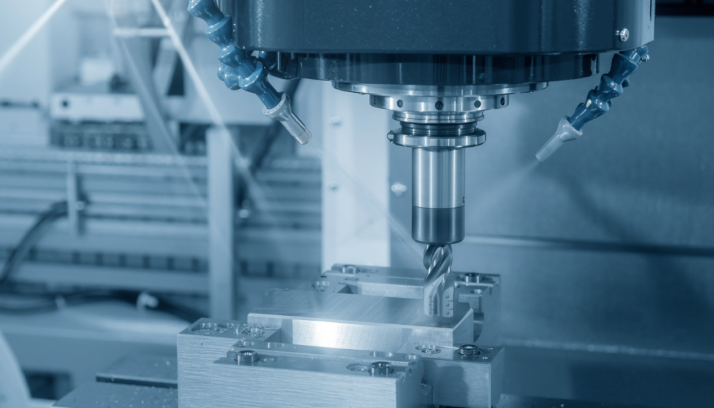 Close-up van een CNC-freesmachine tijdens de metaalbewerking, met een frees boven een vastgeklemd werkstuk en koelvloeistofsproeiers