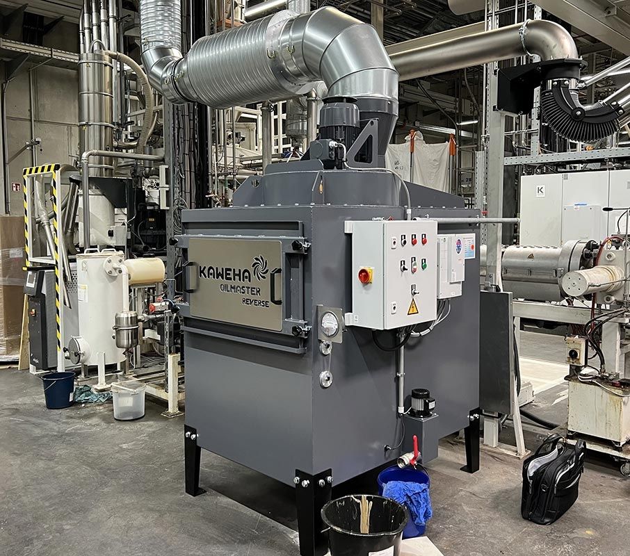 Absauganlage in einer Produktionshalle, angeschlossen an metallene Rohrleitungen, mit seitlichem Schaltschrank und aufgesetztem Motor