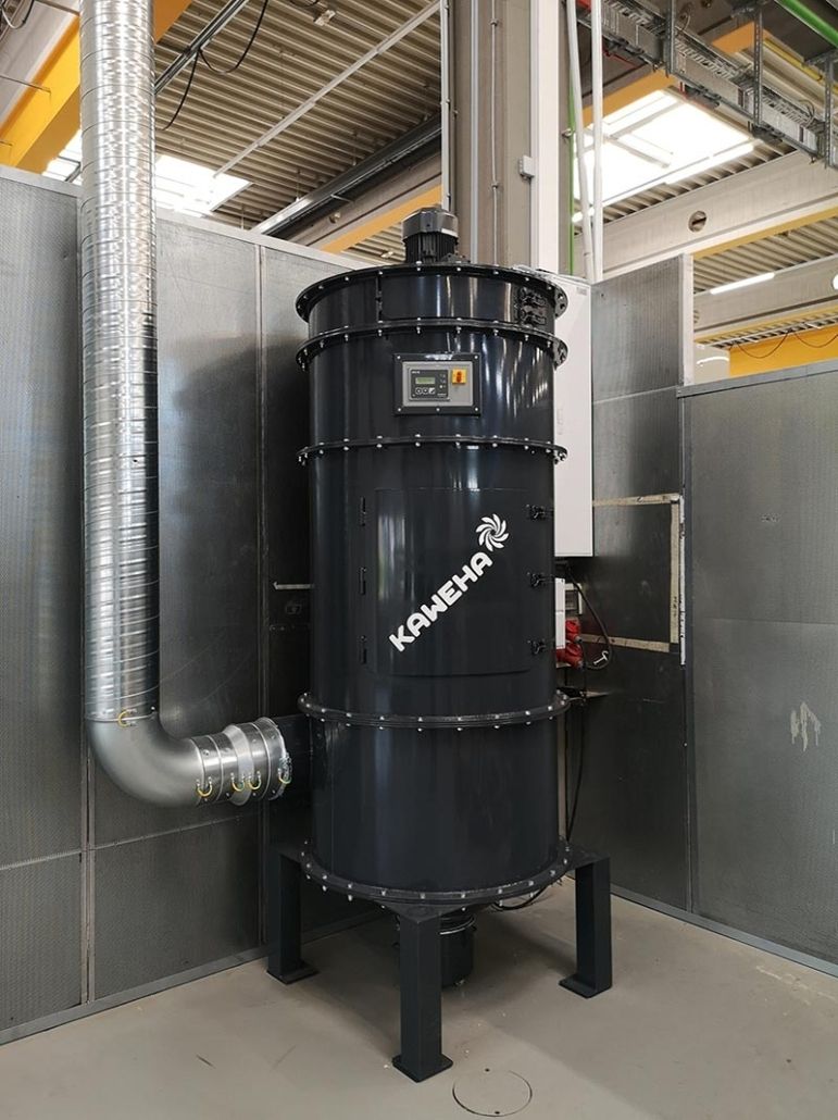Staubfilteranlage in zylindrischer Bauform, an einer Wand aufgestellt und über eine seitliche Rohrleitung angeschlossen